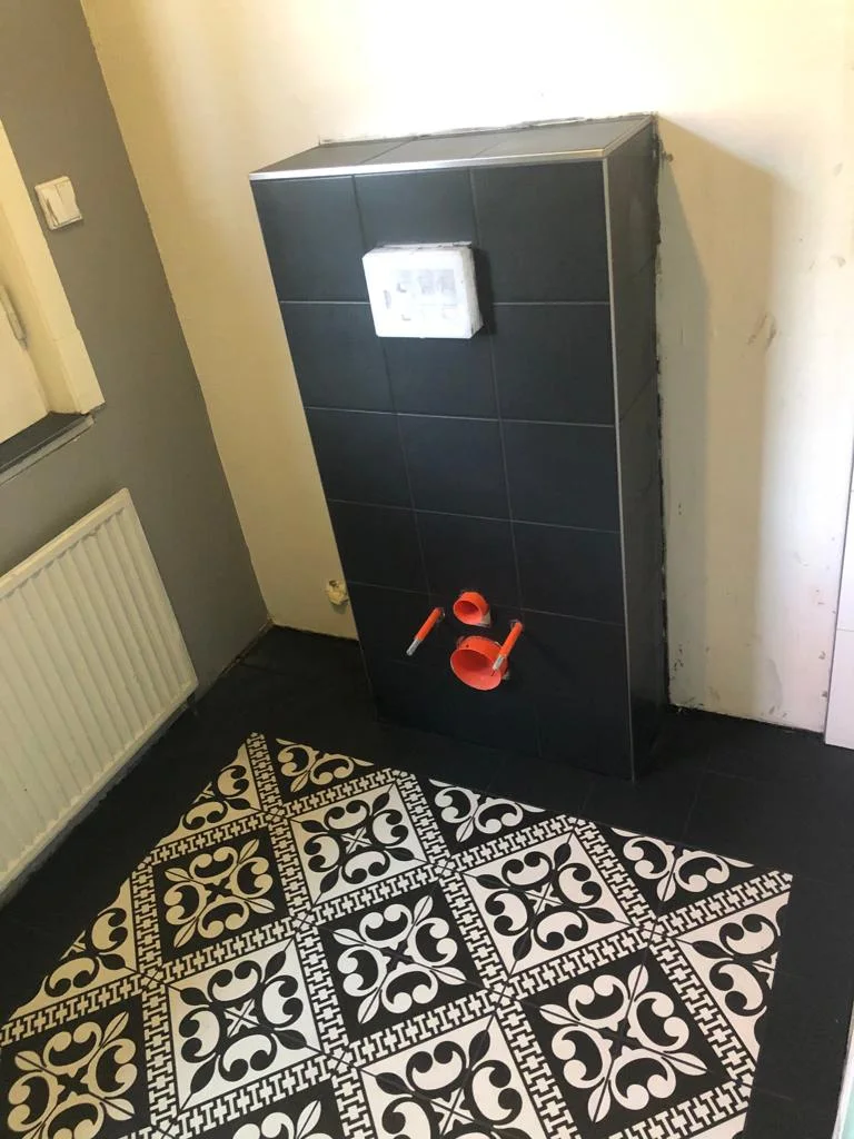 WC mit schwarzen Wandfliesen und gemusterten Bodenfliesen